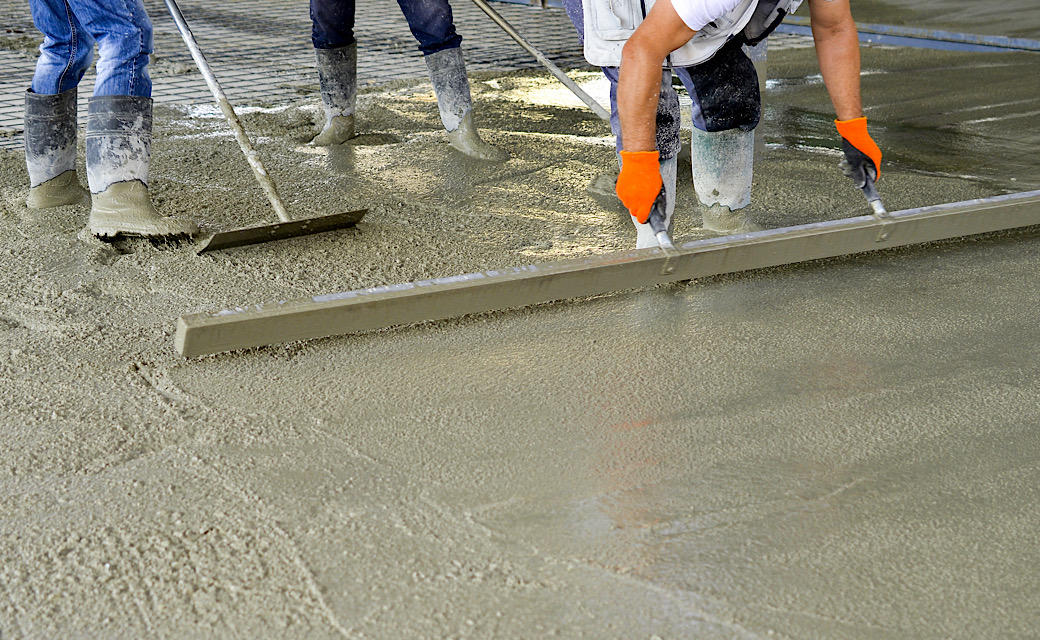 Construction workers leveling concrete of a new foundation.